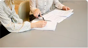 Two people signing property documents at a desk