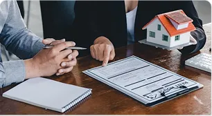 An adviser reviewing estate documents beside a model house